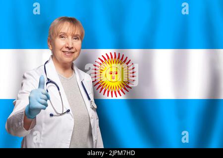 Donna argentina sorridente medico maturo con stetoscopio sulla bandiera di sfondo Argentina Foto Stock