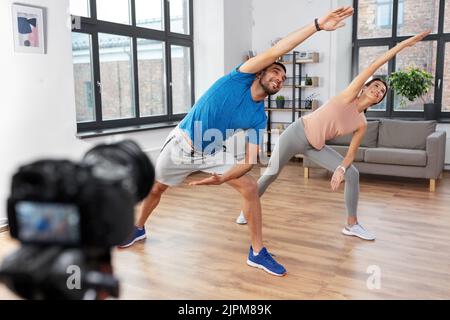 coppia che registra il video della lezione di yoga a casa Foto Stock