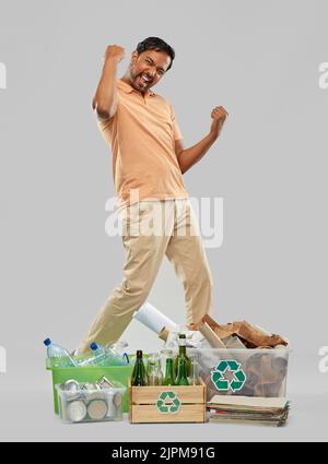 uomo sorridente che smista carta, vetro e rifiuti di plastica Foto Stock