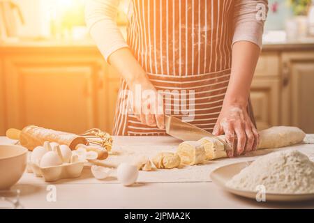 Vista ravvicinata di due donna di mani tagliate la pasta a coltello Foto Stock