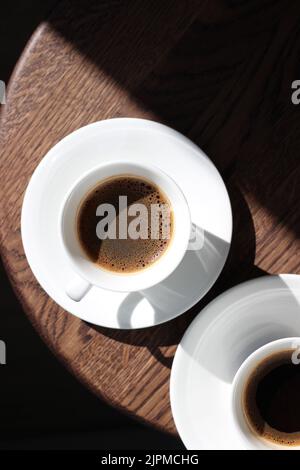 Espresso in tazze bianche in ceramica su sgabello rotondo in legno. Bere caffè. Foto Stock