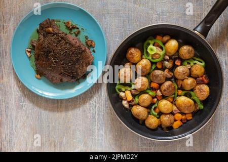 Grande pezzo di carne di prosciutto fritto in una padella con verdure e spezie, pranzo americano fritto pezzo di carne e patate, fagioli in salsa e snack, copia sp Foto Stock