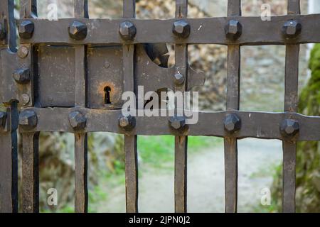 Vecchio dettaglio della serratura sulle barre di ferro. Castello di Pernstejn, Repubblica Ceca, Europa. Cortile sfocato sullo sfondo, HD, carta da parati 4K. Esempio di fabbro ar Foto Stock