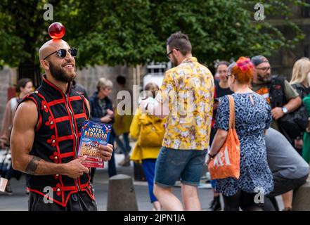 Edimburgo, Scozia, Regno Unito, 19th agosto 2022. Artisti fringe sul Royal Mile: La strada è piena di fringe-goers, artisti di strada e cast di spettacoli che distribuiscono volantini in una giornata di sole. Nella foto: Un circo performer da Lost in Translation Hotel Paradiso spettacolo circo. Credit: Sally Anderson/Alamy Live News Foto Stock