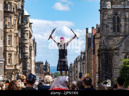 Edimburgo, Scozia, Regno Unito, 19th agosto 2022. Fringe Performers on the Royal Mile: La strada è piena di fringe-goers, artisti di strada in una giornata di sole. Nella foto: Un giocoliere di spada. Intrattiene la folla credito: Sally Anderson/Alamy Live News Foto Stock