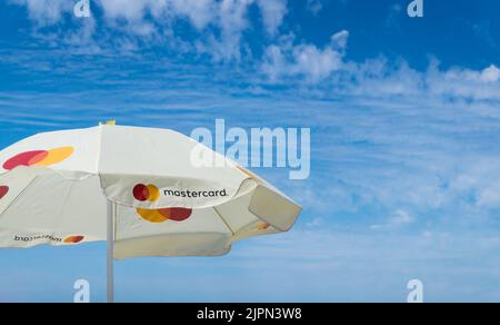 Logo Mastercard su ombrellone blu cielo con spazio copia. Utilizzo della carta di credito o di debito per pagare il concetto di vacanza. Batumi, Georgia - 2 luglio 2021 Foto Stock
