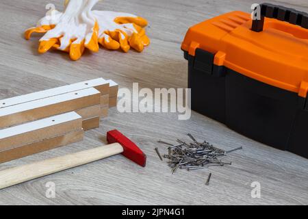 Cassetta degli attrezzi su pavimento in legno . Truciolato, martello e chiodi. Foto Stock