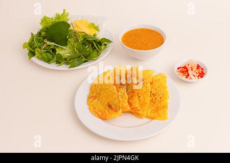 Banh xeo, Crêpes vietnamita o pancake con maiale, gamberetti, cipolle, germogli di api all'interno e salsa di pesce. Cibo vietnamita isolato su sfondo bianco; Foto Stock