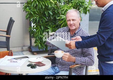 Cameriere che dà computer tablet con lettore di carte collegato al visitatore caffè Foto Stock