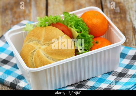 Pranzo sano a scuola contenente un rotolo con formaggio, lattuga, pomodoro, mandarini succosi Foto Stock