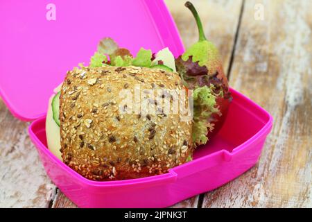 Lunchbox contenente panino intero con formaggio svizzero, lattuga, cetriolo e pera Foto Stock