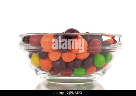 Tante caramelle dolci e colorate in un piatto di vetro, primo piano, isolate su fondo bianco. Foto Stock