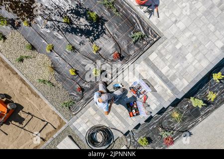 Caucasian Professional Garden Systems Technician Installing Drip Irrigation in Residential Backyard Garden di recente sviluppo. Lavoro di paesaggista. Foto Stock