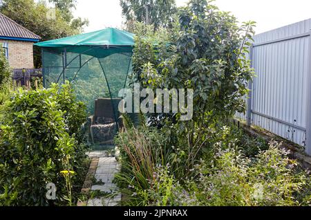 Gazebo sotto una griglia di zanzara su un esterno. Posto per riposare nel cortile posteriore Foto Stock
