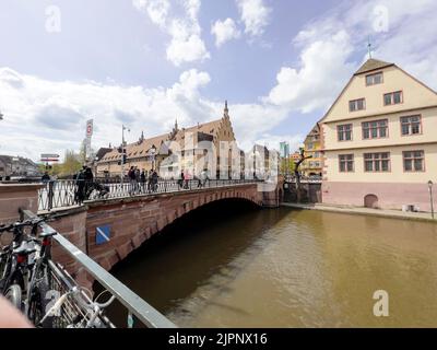 Strasburgo, Francia - 10 aprile 2022: Pedoni locali e turisti a piedi sul Pont du Corbeau con l'architettura alsaziana in background - visite turistiche Strasburgo Foto Stock