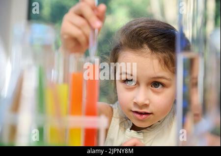 Piccola ragazza eccitata che usa la chimica impostata in classe di scienza elementare. Schoolgirl fa esperimenti chimici scientifici Foto Stock