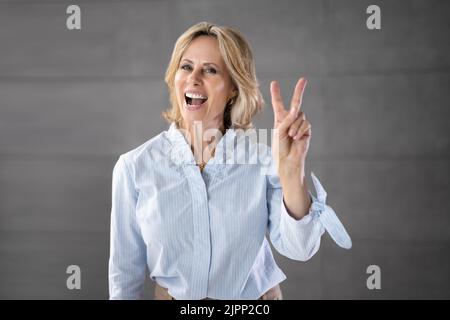 Nonna fredda Donna anziana. Persona anziana con segno V Finger Foto Stock
