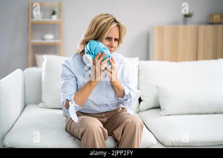 Giovane donna sconvolto guancia a contatto con sacco di acqua fredda a casa Foto Stock