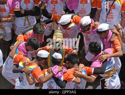 Mumbai, India. 19th ago, 2022. I devoti indù si riuniscono intorno ad un uomo vestito come Lord Vithoba durante il festival Janmashtami a Mumbai. Janmashtami è celebrata per celebrare la nascita di Lord Krishna. I devoti indù si riuniscono per le strade e formano piramidi acrobatiche per rompere dahi handi (vaso di terra riempito di cagliata) celebrando l'occasione. (Foto di Ashish Vaishnav/SOPA Images/Sipa USA) Credit: Sipa USA/Alamy Live News Foto Stock