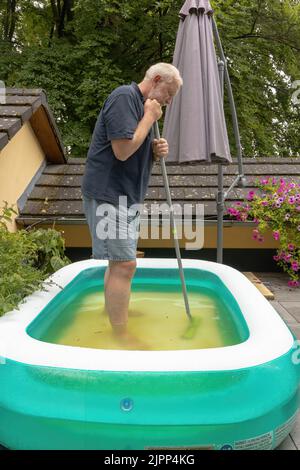 l'uomo pulisce una piscina sul terrazzo Foto Stock