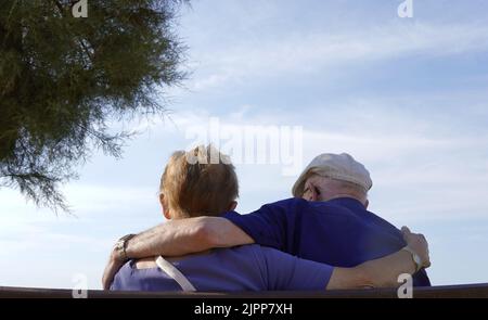 Coppia anziana che si abbraccia da dietro. Sfondo cielo blu Foto Stock