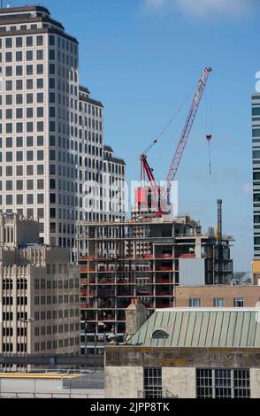 Austin Texas USA, agosto 2 2022: Una gru luffing si trova in cima allo scheletro di un hotel a 28 piani presto in via di costruzione, racchiuso tra due altri edifici alti del centro città. Ci sono almeno due dozzine di edifici in costruzione nel centro della città con molti altri sulla tavola da disegno. ©Bob Daemmrich Foto Stock