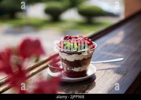 Vegan naturale, fresco, sano, a strati, senza zucchero di muesli con frutta fresca e frutti di bosco in terrazza. Mangiare sano in giardino. Foto Stock