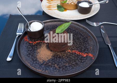 torta di lava. Fondente al cioccolato con ganache al basilico. Dessert tradizionale di cucina francese con ripieno d'autore. Foto Stock