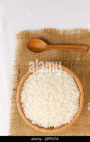 Asciugare il riso camolino in una ciotola di legno. Il concetto di alimentazione sana. Stile rustico. Messa a fuoco selettiva. Orientamento verticale. Vista dall'alto. Foto Stock