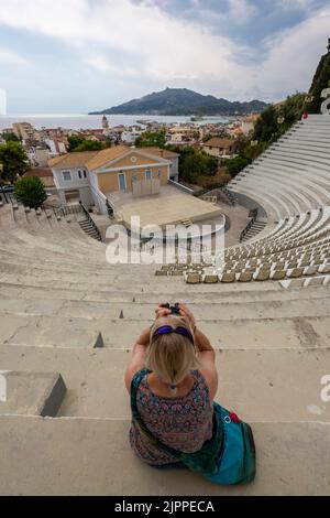 giovane donna seduta guardando fuori sul teatro all'aperto nella città greca di zante, anfiteatro su zante, locale di intrattenimento della città di zante, teatro Foto Stock