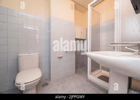 Bagno semplice con box doccia piastrellato bianco, porte scorrevoli, bagni bianchi e piastrelle blu Foto Stock