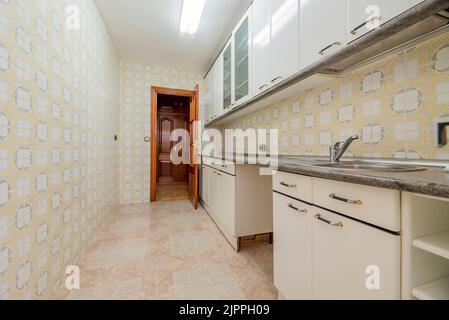 Cucina con armadi in legno lucido bianco, ripiani in granito grigio e piastrelle vintage Foto Stock