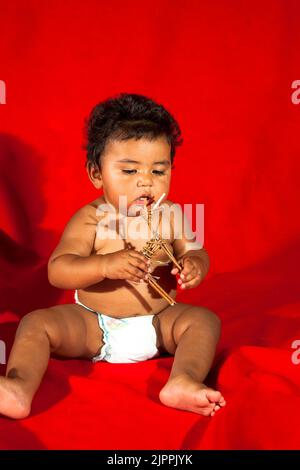 Il bambino nativo americano, dal Pueblo di Santa Clara nel New Mexico, gioca con una figura del bastone di ramoscello di un animale quale un cervo che era un tradizionale a. Foto Stock