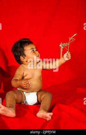 Il bambino nativo americano, dal Pueblo di Santa Clara nel New Mexico, gioca con una figura del bastone di ramoscello di un animale quale un cervo che era un tradizionale a. Foto Stock