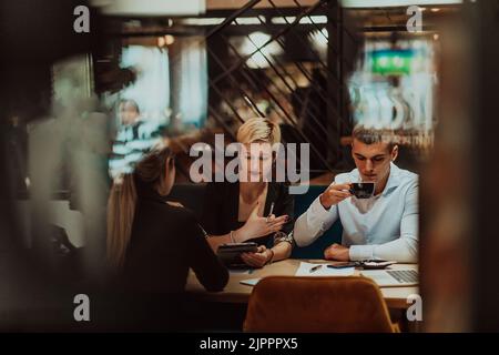 Buon uomo d'affari sorridente allegro durante una riunione in una caffetteria. Gruppo di professionisti di successo che lavorano come una squadra in un Foto Stock
