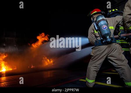 I marinai assegnati all'unità di pre-messa in servizio (PCU) John F. Kennedy (CVN 79) combattono un incendio simulato durante l'addestramento antincendio presso la scuola antincendio dei guerrieri. La scuola conduce corsi di addestramento antincendio e di controllo dei danni, ospitando centinaia di studenti ogni settimana. John F. Kennedy è la seconda portaerei di classe Ford ed è in costruzione presso il cantiere navale Huntington Ingalls Industries Newport News. Foto Stock