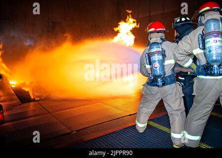 I marinai assegnati all'unità di pre-messa in servizio (PCU) John F. Kennedy (CVN 79) combattono un incendio simulato durante l'addestramento antincendio presso la scuola antincendio dei guerrieri. La scuola conduce corsi di addestramento antincendio e di controllo dei danni, ospitando centinaia di studenti ogni settimana. John F. Kennedy è la seconda portaerei di classe Ford ed è in costruzione presso il cantiere navale Huntington Ingalls Industries Newport News. Foto Stock