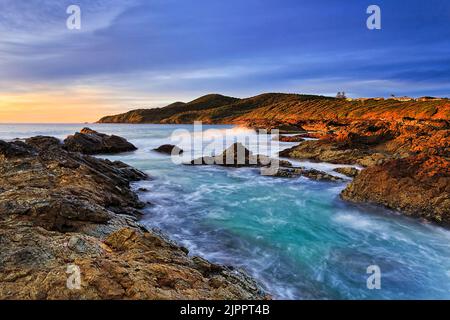 Rocce di arenaria illuminata dal sole sulla spiaggia di Burgess della città di Forster in Australia - oceano Pacifico a metà costa nord. Foto Stock