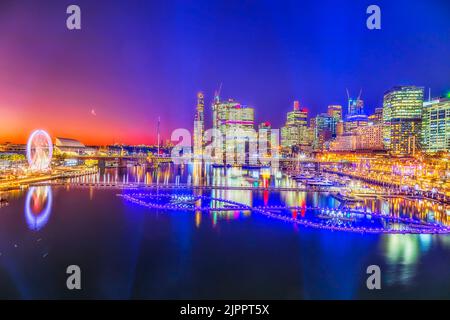 Luminoso e colorato tramonto panoramico sulla City of Sydney, quartiere dei divertimenti del Darling Harbour intorno alle acque cristalline della Cockle Bay che riflette le illuminazioni Foto Stock