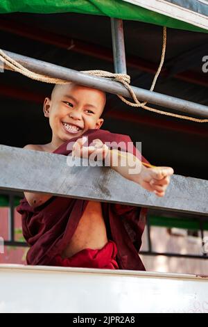 Un sorridente monaco novizio suona in un monastero buddista di Nyaung U, Bagan, Birmania. Foto Stock