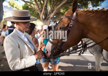 Malaga, Spagna. 19th ago, 2022. Una donna di cavalli è vista guardando il suo cavallo come partecipa alla fiera di Malaga 2022 alla fiera 'Cortijo de Torres' recinzione. Dopo due anni di cancellazione a causa della pandemia di coronavirus, migliaia di persone si riuniscono nelle strade principali della città per partecipare alla Fiera di Malaga in un'atmosfera festosa. Tra una settimana, migliaia di turisti e abitanti del luogo potranno assistere a concerti, balli di flamenco per le strade e altre attività come la fiera della corrida o gli spettacoli di cavalli. (Foto di Jesus Merida/SOPA Images/Sipa USA) Credit: Sipa USA/Alamy Live News Foto Stock