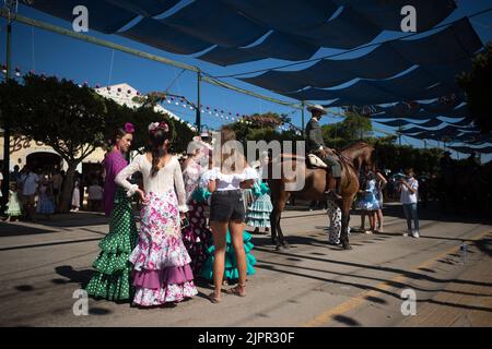 Malaga, Spagna. 19th ago, 2022. Un gruppo di giovani è visto indossare abiti flamenco chiacchierare mentre prendono parte alla fiera di Malaga 2022 alla fiera 'Cortijo de Torres' recinto. Dopo due anni di cancellazione a causa della pandemia di coronavirus, migliaia di persone si riuniscono nelle strade principali della città per partecipare alla Fiera di Malaga in un'atmosfera festosa. Tra una settimana, migliaia di turisti e abitanti del luogo potranno assistere a concerti, balli di flamenco per le strade e altre attività come la fiera della corrida o gli spettacoli di cavalli. (Credit Image: © Jesus Merida/SOPA Images via ZUMA Press Wire) Foto Stock