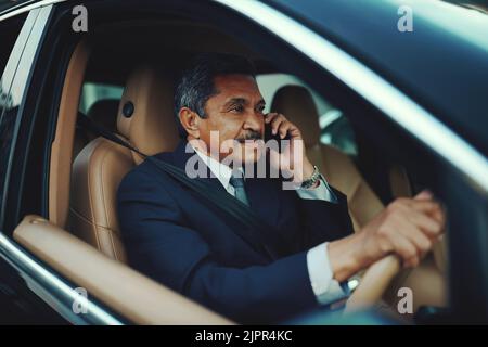 Continua a andare, continua a crescere il successo. Un uomo d'affari maturo che usa il telefono mentre viaggia in auto. Foto Stock