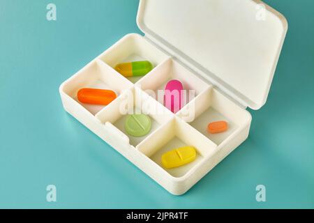 Sei diversi pezzi di medicina colorata in una scatola di medicina pillole giornaliere Foto Stock