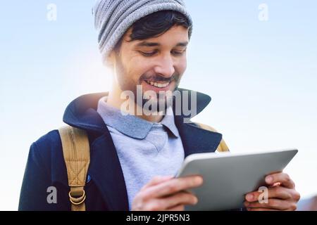 Ovunque tu vada, resta connesso. Un giovane uomo che usa un tablet digitale mentre sei in città. Foto Stock