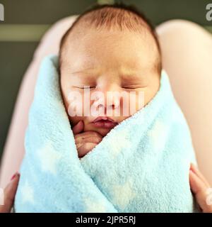 Sembra così comodo: Un ragazzino stanco che dorme con gli occhi chiusi mentre sua madre lo tiene in mano a casa. Foto Stock