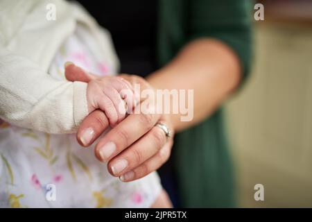 Le ceneri hanno ottenuto una stretta ferma sul cuore di Moms. Colpo di primo piano di una madre che tiene la sua piccola mano delle bambine. Foto Stock