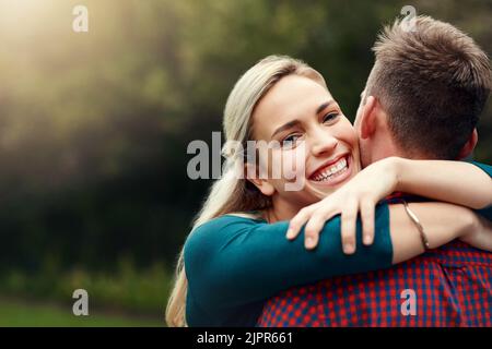 Il mio posto felice è nel suo abbraccio. Ritratto di una giovane coppia affettuosa che trascorre del tempo di qualità insieme all'aperto. Foto Stock