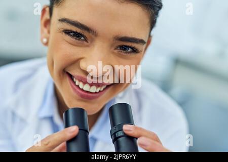 Scopriamo qualcosa di nuovo. Ritratto di un giovane scienziato utilizzando un microscopio in laboratorio. Foto Stock