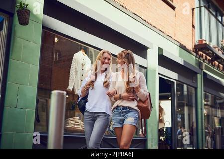 A piedi in città. Inquadratura a basso angolo di due giovani simpate amiche che esplorano una città straniera. Foto Stock